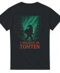 Svart t-shirt med silhuett av tomte i skogen under norrsken, texten "I Believe in Tomten"