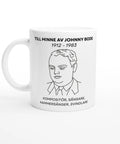 Vit mugg med linjeteckning av Johnny Bode och text till hans minne