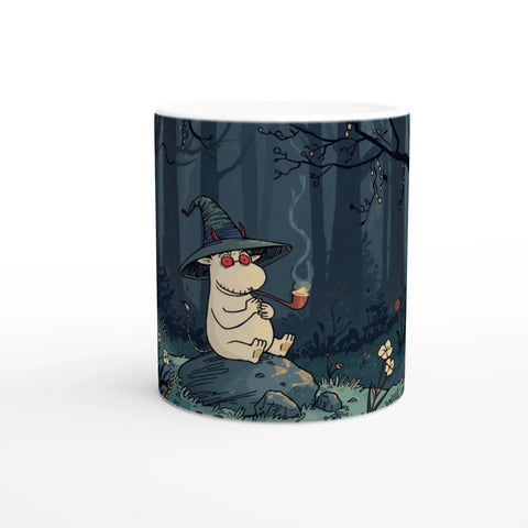 Keramisk mugg med roligt stenat troll sittandes i en skog, humoristiskt motiv på vit mugg. Parodi på mumin.