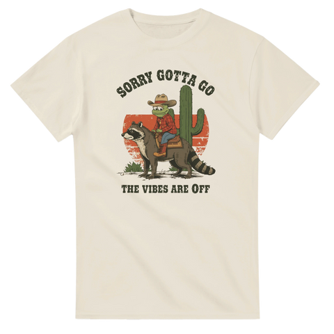 Beige t-shirt med cowboy som rider på tvättbjörn och texten Sorry Gotta Go The Vibes Are Off