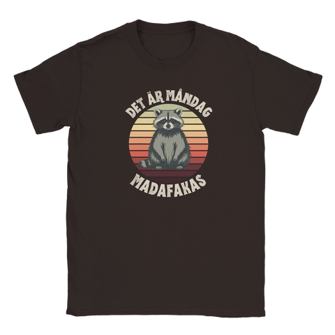 Brun t-shirt med tecknad tvättbjörn mot retro solnedgång och texten Det är måndag madafakas