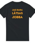 T-shirt med humoristiskt tryck ”Jag Bara Låtsas Jobba” i retro gul text – perfekt som kontorsskämt eller AW-plagg.
