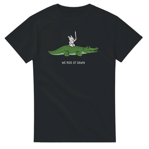 Komisk t-shirt med tecknad kanin som rider på en krokodil med svärd och texten “We ride at dawn”