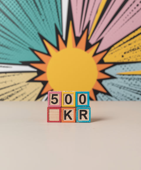 Träklossar som visar 500kr placerade framför en gul sol i popkonststil